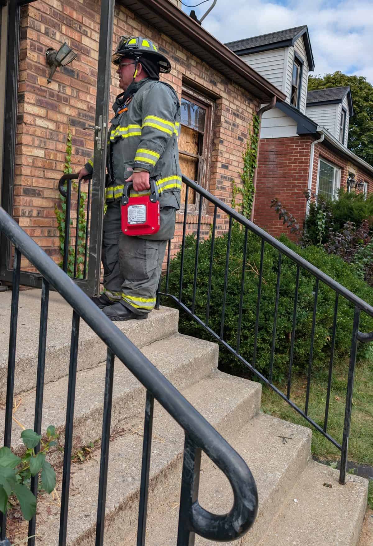 Firefighter carrying the red FS2-MAX up the front steps